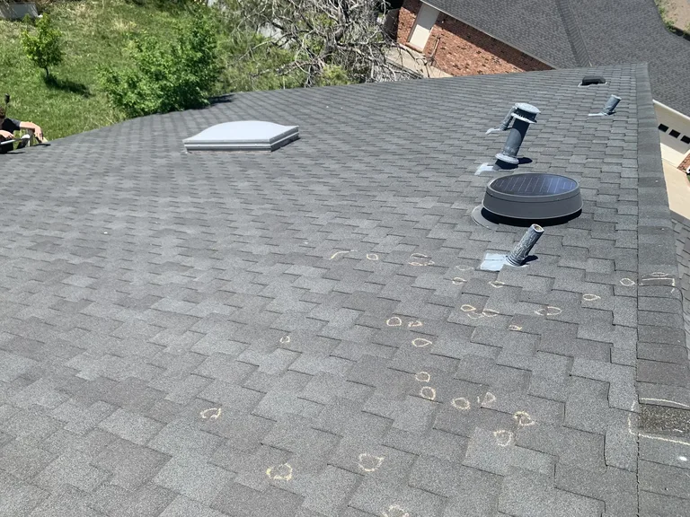 Wide aerial of a gray architectural shingle roof with numerous hail strikes circled in chalk plus vents and skylight — strong hail-inspec... — 5 Star Roofing